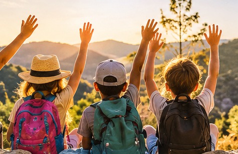 Des enfants de dos, bras levés, face à un paysage au soleil couchant